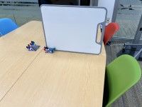 Whiteboard standing up on its side in middle of table from marker cup