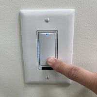 Light switch with finger holding down bottom of button